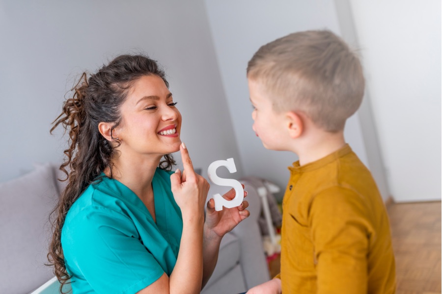 speech pathologist teaching a little boy an S sound