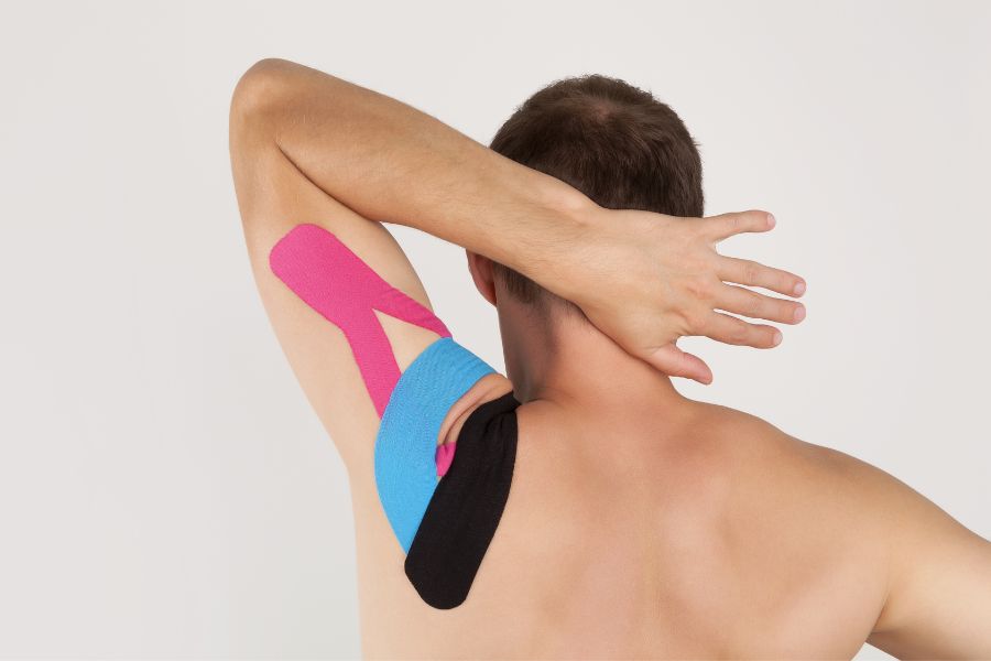 man that has had kinesiology tape applied to left shoulder
